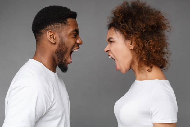 Relationship crisis. Young african-american couple yelling at each other on gray studio background