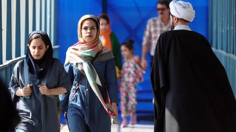 Two young Iranian women walk past a cleric in Tehran, Iran/Reuters