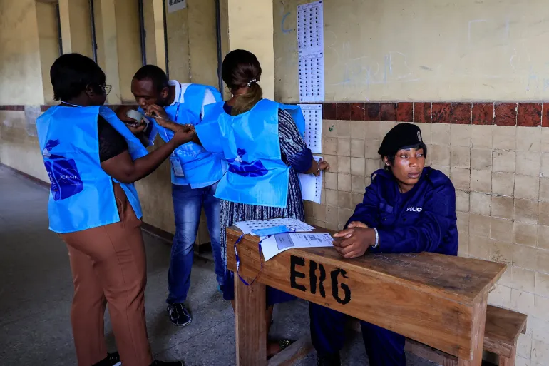 Election officials sticks voters list on the wall as election is set to commence in Kinshasa on December 20, 2023/Reuters