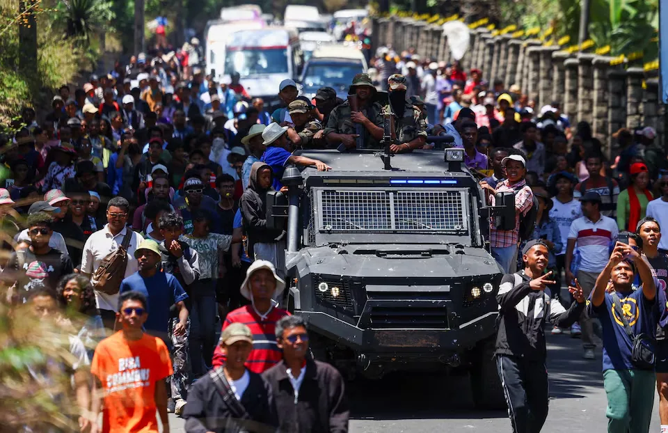 Demonstrators walk next to a Madagascan armed forces vehicle during a countrywide demonstration led by young people against recurring electricity cuts and insufficient water supply, in Antananarivo, Madagascar, October 13, 2025. REUTERS/Siphiwe Sibeko