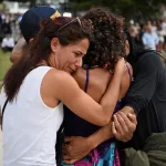 Visitors sorrowfully embrace at a temporary memorial created after an assault on a Jewish holiday gathering at Bondi Beach in Sydney, Australia, on December 15, 2025/ REUTERS/Flavio Brancaleone