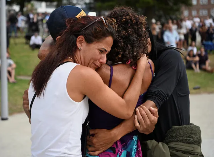 Visitors sorrowfully embrace at a temporary memorial created after an assault on a Jewish holiday gathering at Bondi Beach in Sydney, Australia, on December 15, 2025/ REUTERS/Flavio Brancaleone