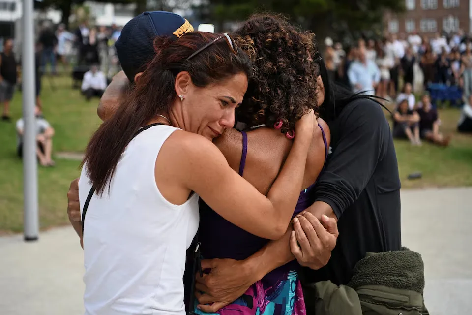 Visitors sorrowfully embrace at a temporary memorial created after an assault on a Jewish holiday gathering at Bondi Beach in Sydney, Australia, on December 15, 2025/ REUTERS/Flavio Brancaleone