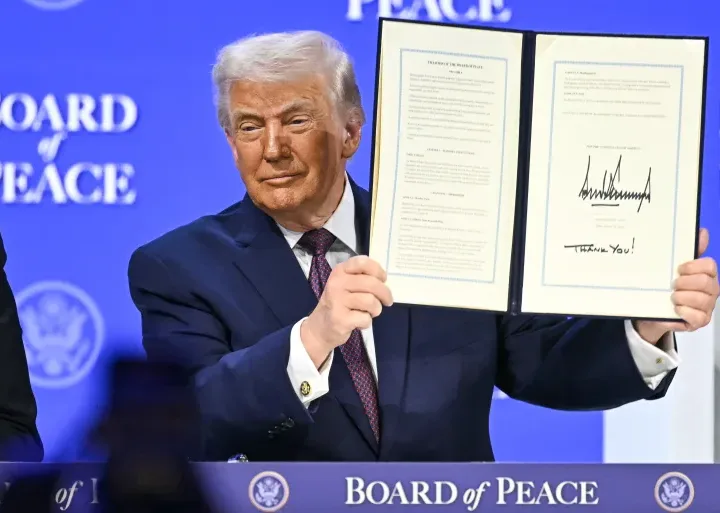 Donald Trump, the US President, displays a signed founding charter for the Board of Peace at the World Economic Forum in Davos, Switzerland, on January 22, 2026 [AFP]