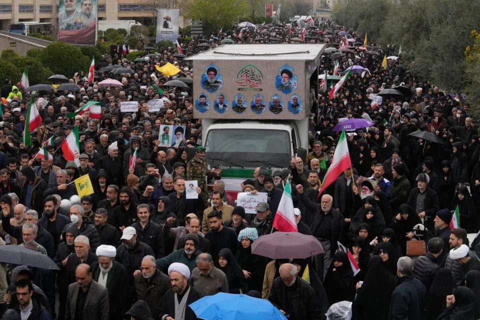 Mourners line the streets of Tehran as a truck bearing the coffins of Iranian Intelligence Minister Esmail Khatib, along with his wife and daughter, passes through the city during a funeral procession on Friday, March 20, 2026. (AP Photo/Vahid Salemi)