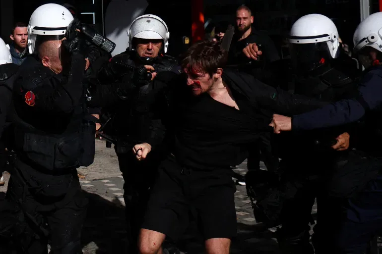 Albanian students stage an anti-government protest in Tirana as police officers restrain a demonstrator. [Florion Goga/Reuters]
